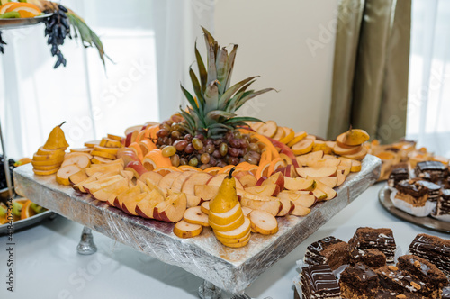 Fruit slicing at a wedding banquet. Watermelon, grapes, strawberry, orange, plum, pear, dinha, peach, kiwi, pineapple, persimmon, apple photo