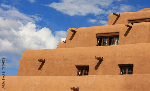 Pueblo adobe stucco stepped or tiered building. Contoured adobe plaster architecture with timber wood vigas. Southwest USA, New Mexico