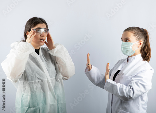 Female doctor in white uniform getting away from a woman in defensive coat
