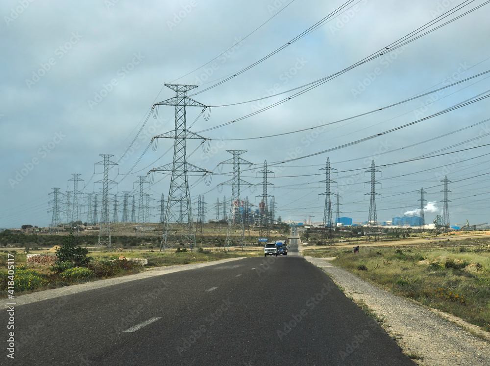 Power plant and masts near asphalt route. Route near power plant and electric masts with electric lines. Power plant and masts near asphalt route. Route near power plant and electric masts with electric lines.