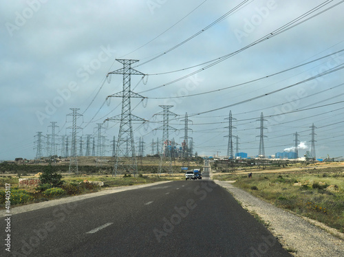Power plant and masts near asphalt route. Route near power plant and electric masts with electric lines.