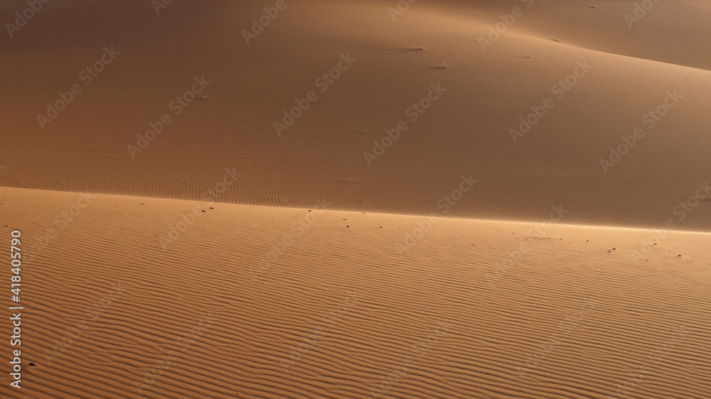 Naklejka premium Sand background and wave pattern on the sand as texture in the foreground. 