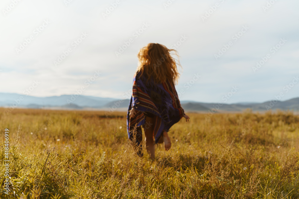 on the steppe grass in the distance to the hills runs barefoot girl with disheveled winds of hair. High quality photo on the steppe grass in the distance to the hills runs barefoot girl with disheveled winds of hair. High quality photo
