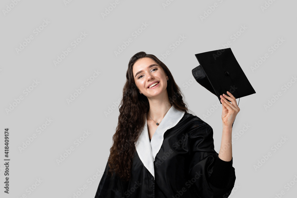 Graduate girl with master degree in black graduation gown and cap on white background. Distance learning online. Study at home. Graduation from college. Graduate girl with master degree in black graduation gown and cap on white background. Distance learning online. Study at home. Graduation from college.