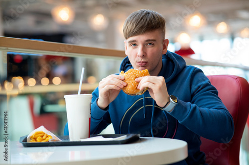 Fotografija Dissatisfied, tasteless food, Young guy eats on a court, fast food