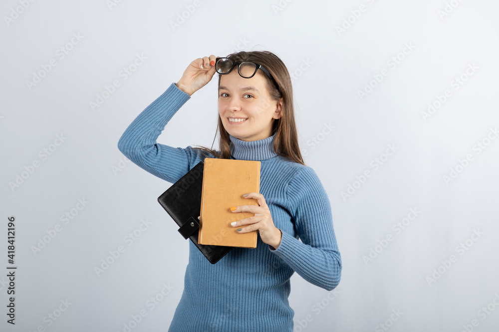 Portrait of a girl in eyeglasses holding two books on white-gray background Portrait of a girl in eyeglasses holding two books on white-gray background