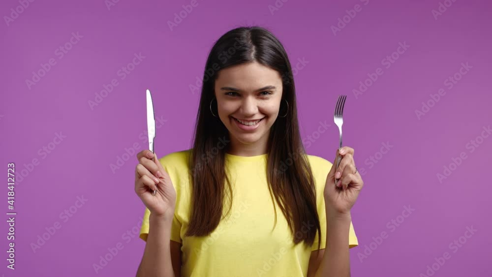 Portrait of pretty hungry woman with fork and knife. Girl waiting for serving dinner dishes with cutlery on pink studio background. Portrait of pretty hungry woman with fork and knife. Girl waiting for serving dinner dishes with cutlery on pink studio background.