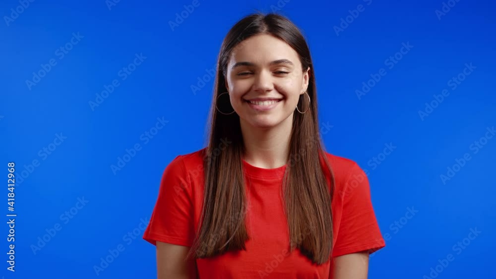 Young pretty woman with long hairstyle looking to camera, flirting. Beautiful model girl in orange on blue studio background. Young pretty woman with long hairstyle looking to camera, flirting. Beautiful model girl in orange on blue studio background.
