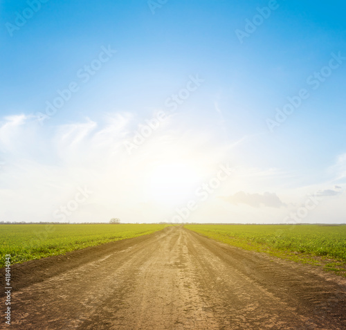 ground road among green fields at the sunset, countryside rural background photo