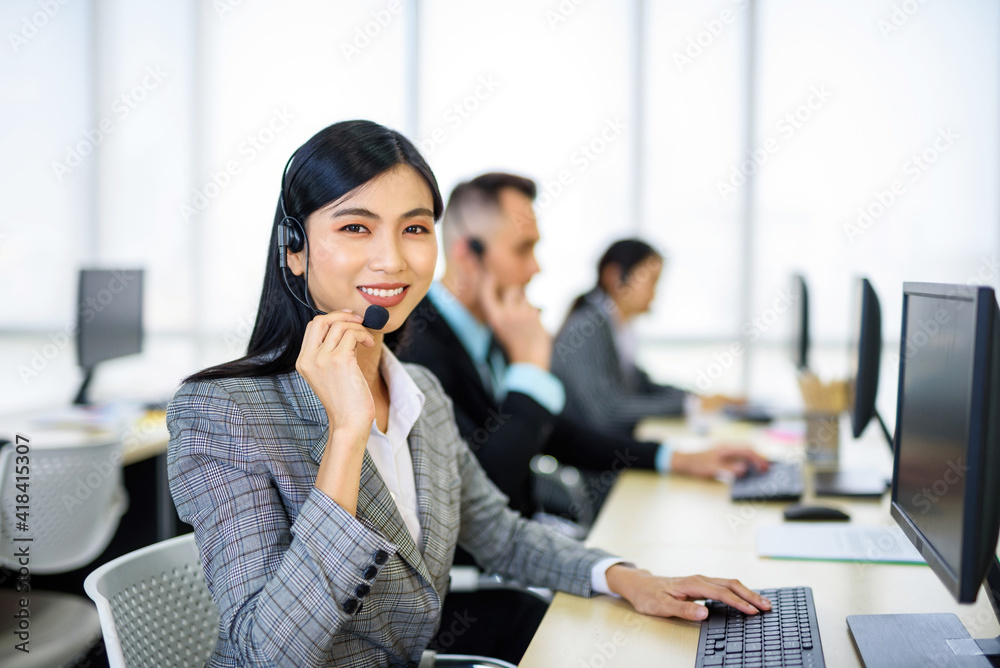 .Asian women public relations or customer service with a hearing aid At her desk looking at the camera And smile. .Asian women public relations or customer service with a hearing aid At her desk looking at the camera And smile.