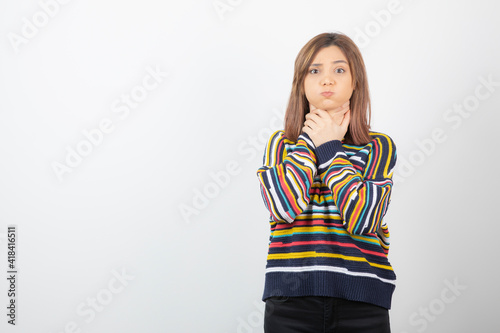 Fotografija Image of a young pretty girl model strangling herself on white-gray wall
