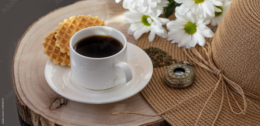 White cup with black coffee. Morning coffee, breakfast, cookies, tropical leaf, wicker hat. Summer sunny background. Breakfast on vacation at the hotel. Traveling at sea, close-up.