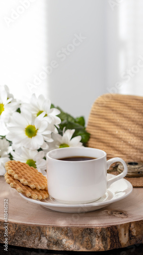 White cup with black coffee. Morning coffee, breakfast, cookies, tropical leaf, wicker hat. Summer sunny background. Breakfast on vacation at the hotel. Traveling at sea, close-up.