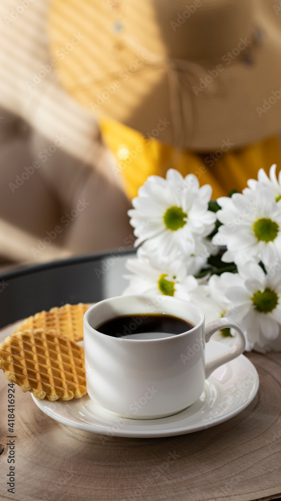 Obraz premium White cup with black coffee. Morning coffee, breakfast, cookies, tropical leaf, wicker hat. Summer sunny background. Breakfast on vacation at the hotel. Traveling at sea, close-up.