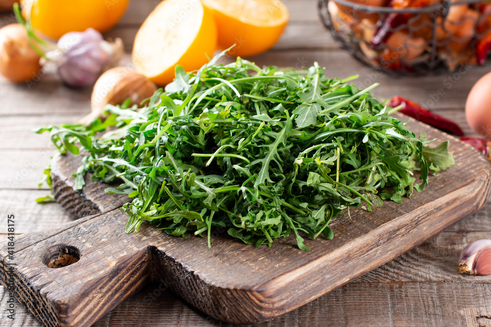 Fresh arugula on rustic wooden background. Fresh arugula, ruccola leaves, rucola, eruca or garden roquette salad Fresh arugula on rustic wooden background. Fresh arugula, ruccola leaves, rucola, eruca or garden roquette salad