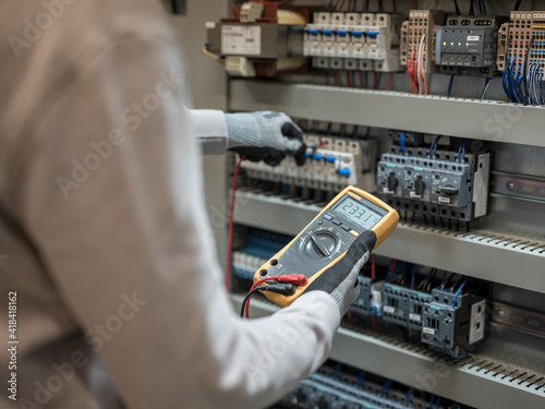 Electricians hands testing current electric in control panel