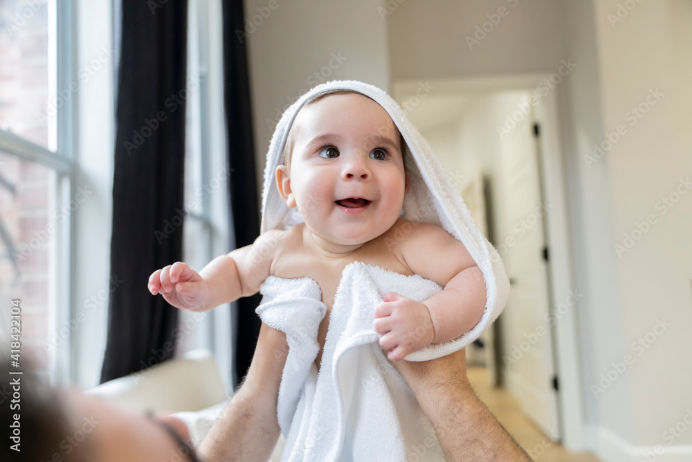 Man holding up cute happy naked baby in white towel Man holding up cute happy naked baby in white towel