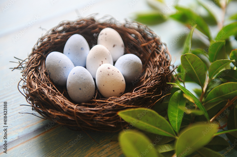 Nest with small eggs. The nest is decorated with green branches. Easter theme. Spring. Scandinavian Easter.