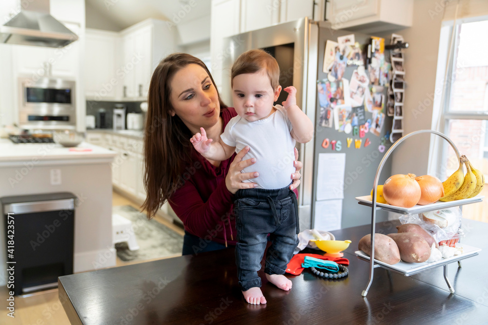 Mom playing with baby boy standing on dining room table Mom playing with baby boy standing on dining room table