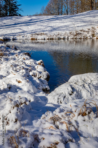 Freshly fallen snow surrounds small pond in winter