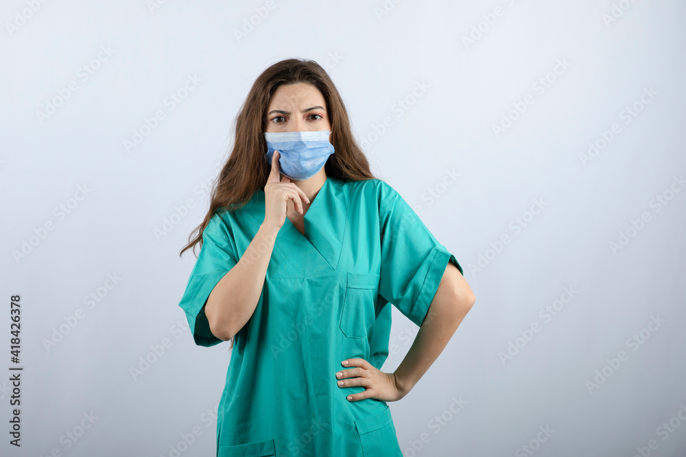Image of a pensive beautiful nurse in green uniform looking away Image of a pensive beautiful nurse in green uniform looking away