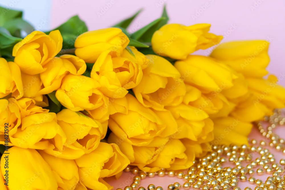 A bouquet of fresh yellow tulips. A bouquet of tulips on a pink background with a scattering of gold beads. Spring flowers in the interior. The concept of spring or holiday, March 8, A bouquet of fresh yellow tulips. A bouquet of tulips on a pink background with a scattering of gold beads. Spring flowers in the interior. The concept of spring or holiday, March 8,
