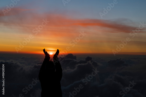 Young woman on top of the mountain holding the sun with her hands during sunset-concept achievement of goals