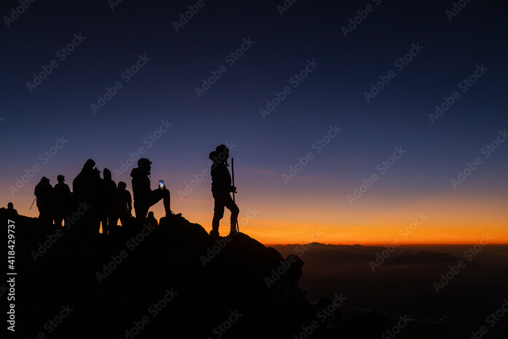 Silhouette woman climber at sunset on top of the Acatenango volcano in Guatemala-young woman reaching the goal of the excursion of her enjoying the last rays of sun on the volcano