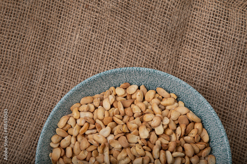 Salted crispy roasted broad beans in blue bowl on linen background