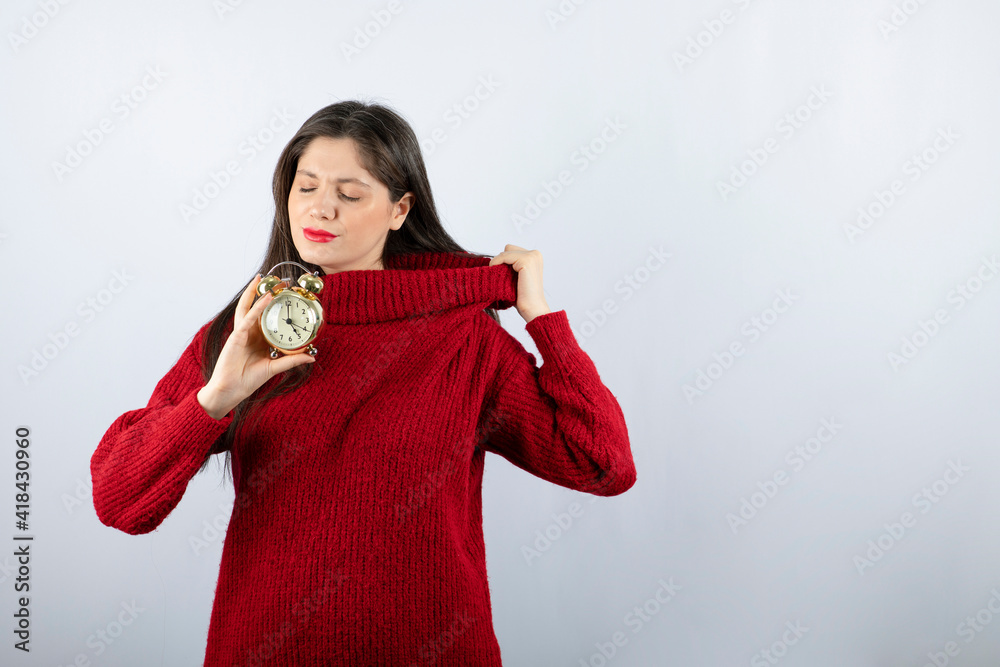 Young beautiful brunette woman holding an alarm clock standing Young beautiful brunette woman holding an alarm clock standing