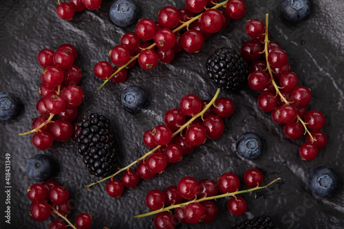 Fresh red currant, blueberries and dewberries on handmade black clay plate