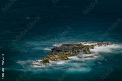 Long exposure on surf along rocky beach, Maui, Hawaii.