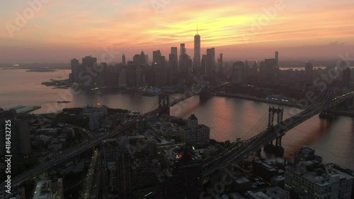 Aerial panning shot of bridges on East river in city against sky, drone flying over modern buildings at sunset - New York City, New York