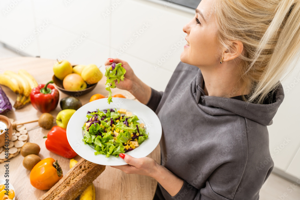Plakat healthy eating, dieting and people concept - close up of young woman eating vegetable salad at home