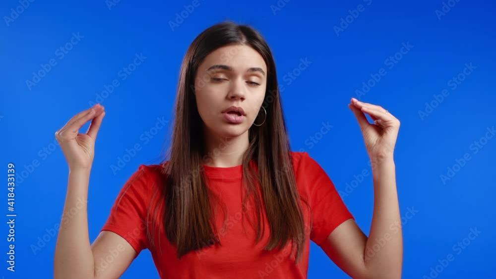 Pretty woman showing bla-bla-bla gesture with hands and rolling eyes isolated on blue background. Empty promises, blah concept. Lier. Pretty woman showing bla-bla-bla gesture with hands and rolling eyes isolated on blue background. Empty promises, blah concept. Lier.