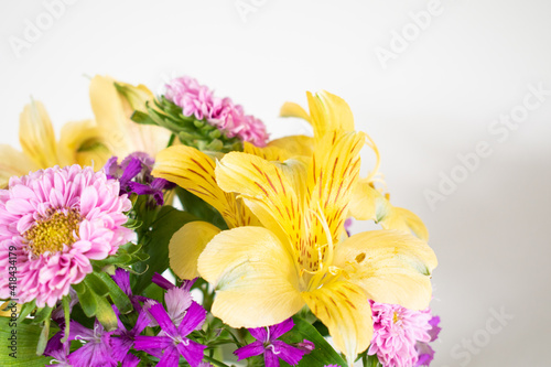 Small pink and yellow flower arrangement of asters and alstromeria in a vase and isolated on white. Colorful spring flower arrangement indoors.  photo