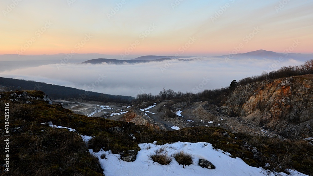 Landscape with dense winter evening fog next to open-cast quarry mine, traces of snow still visible, late winter season. Landscape with dense winter evening fog next to open-cast quarry mine, traces of snow still visible, late winter season.