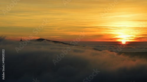 Dramatic sunset with dense fog above hills near Nitra city  western Slovakia. So called Pyramid radio tower visible on tip of Zobor hill. Dense scattered clouds on evening skies. Winter season. 