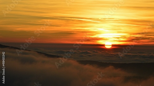 Dramatic sunset on western Slovakia uplands during late winter season, early February. Thick clumps of dense fog visible above hills tips, scattered clouds on the sky.  © zayacsk