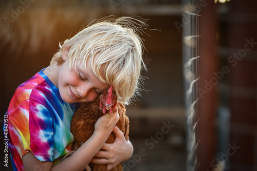 Stock photo image of young Caucasian boy holding isa brown chicken in loving hug with eyes closed