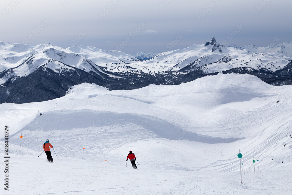 Snow capped mountain vista of Black Tusk and skiers on Whistler, BC.