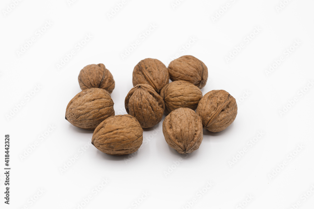 Stack of walnuts piled together isolated on white background with shadows. Close up view, horizontal shot. Stack of walnuts piled together isolated on white background with shadows. Close up view, horizontal shot.