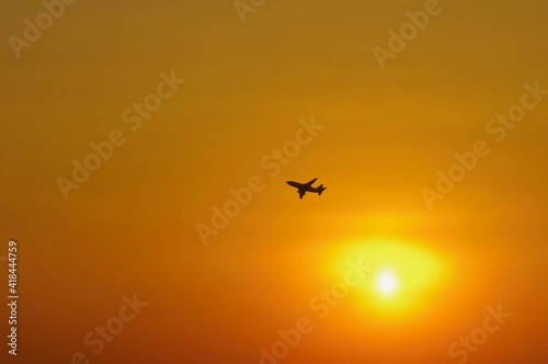 Defocused abstract background of orange sky with a silhouette aeroplane