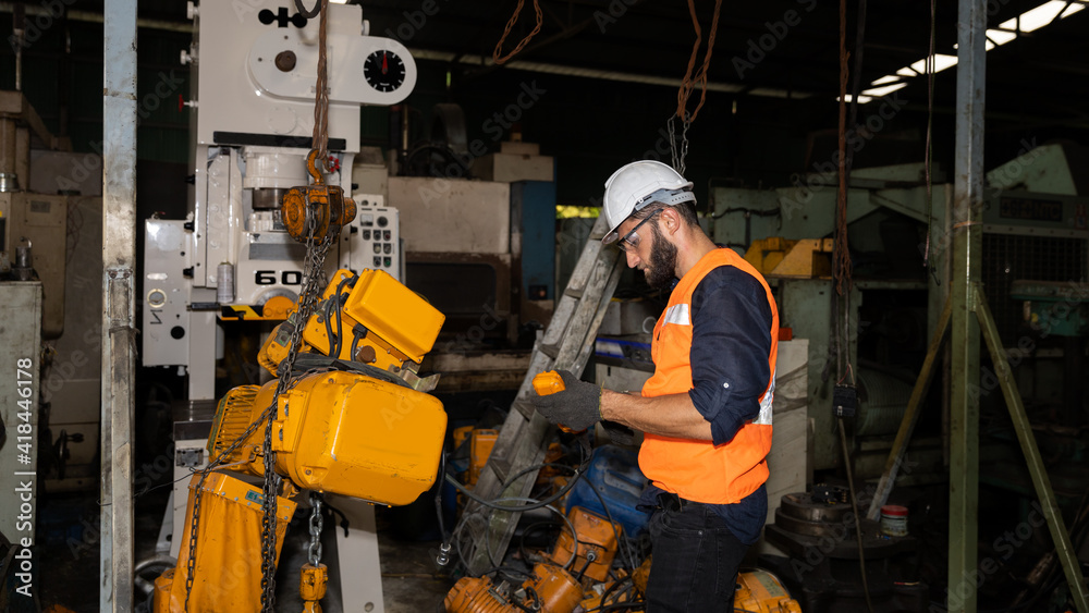 Male mechanical engineer or worker with hardhat and safety uniform checks the operation system in a factory