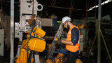 Male mechanical engineer or worker with hardhat and safety uniform checks the operation system in a factory