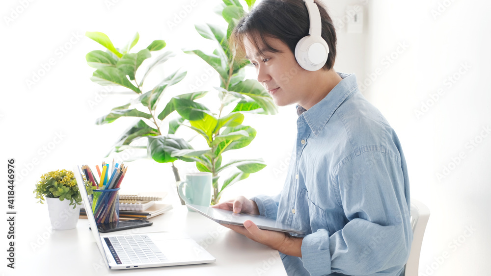 Video conference, Work from home, Asian man making video call to business team with virtual web while holding digital tablet, Contacting colleague by conference on laptop computer at home Video conference, Work from home, Asian man making video call to business team with virtual web while holding digital tablet, Contacting colleague by conference on laptop computer at home