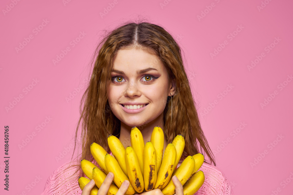 Woman with bananas wavy hair fruits lifestyle bright makeup pink background Woman with bananas wavy hair fruits lifestyle bright makeup pink background
