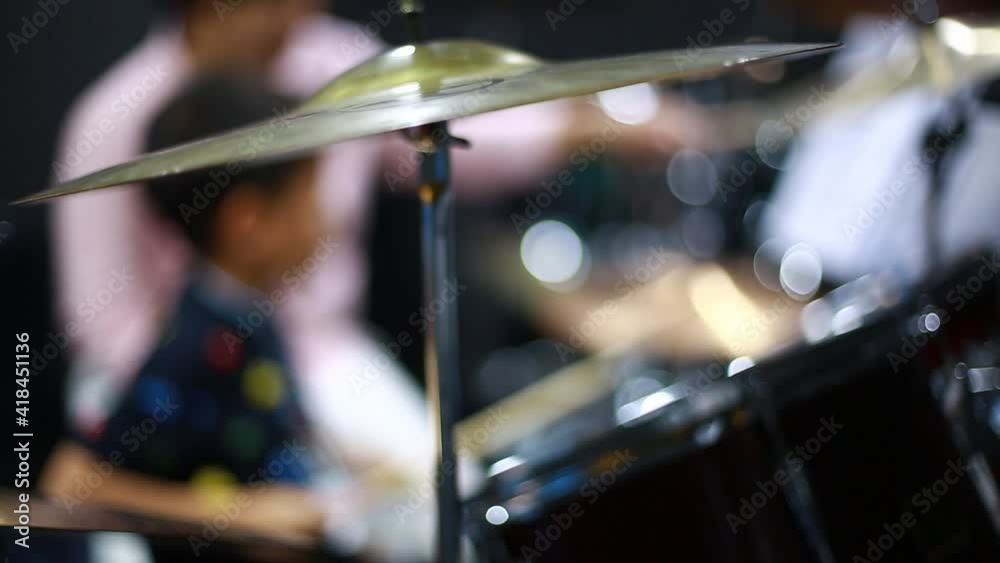 Blurry kid learning and play drum set with teacher in music room. The concept of musical instrument. Blurry music background. Blurry kid learning and play drum set with teacher in music room. The concept of musical instrument. Blurry music background.