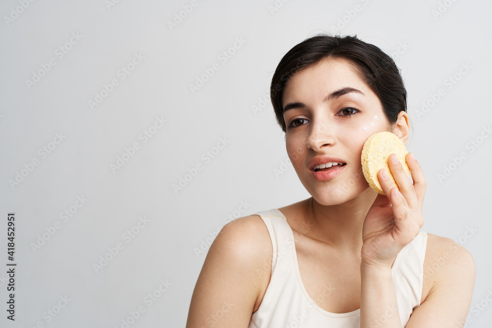 Pretty woman with sponge clean skin facial care close-up