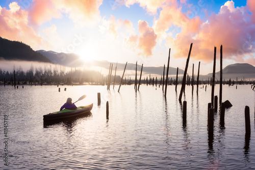 Adventurous Girl kayaking on an infatable kayak in a beautiful lake. Colorful peaceful Sunrise Art Render. Taken in Stave Lake, East of Vancouver, British Columbia, Canada. Adventure and vacation